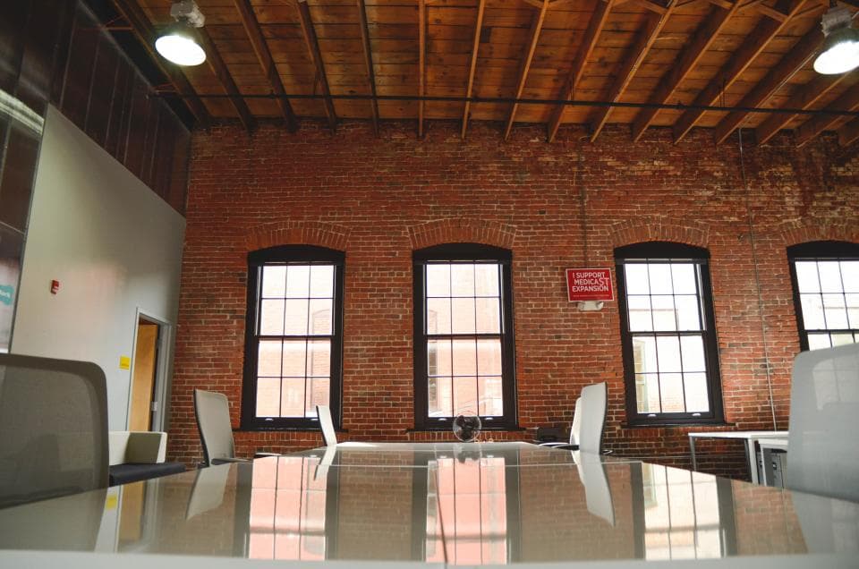 A meeting room with brick walls and tall windows