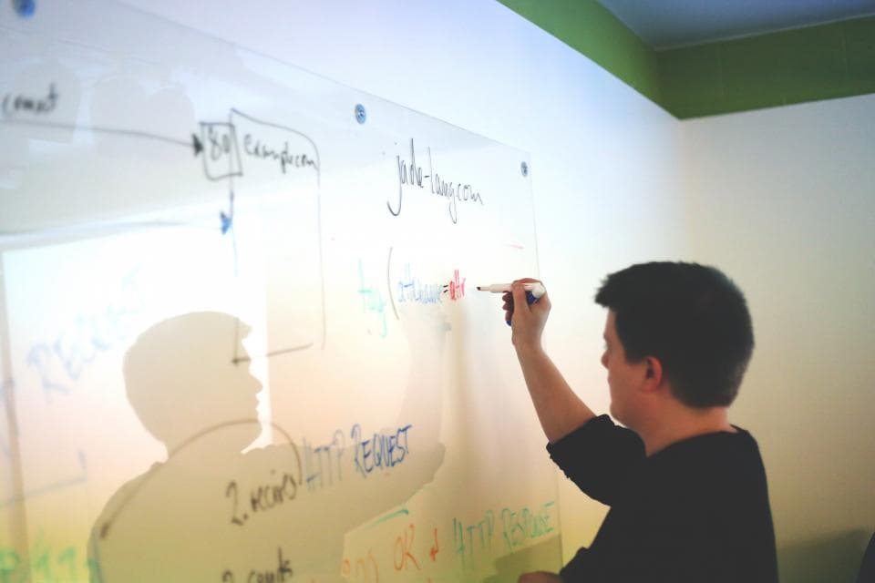 A man sketching a diagram on a glass wall